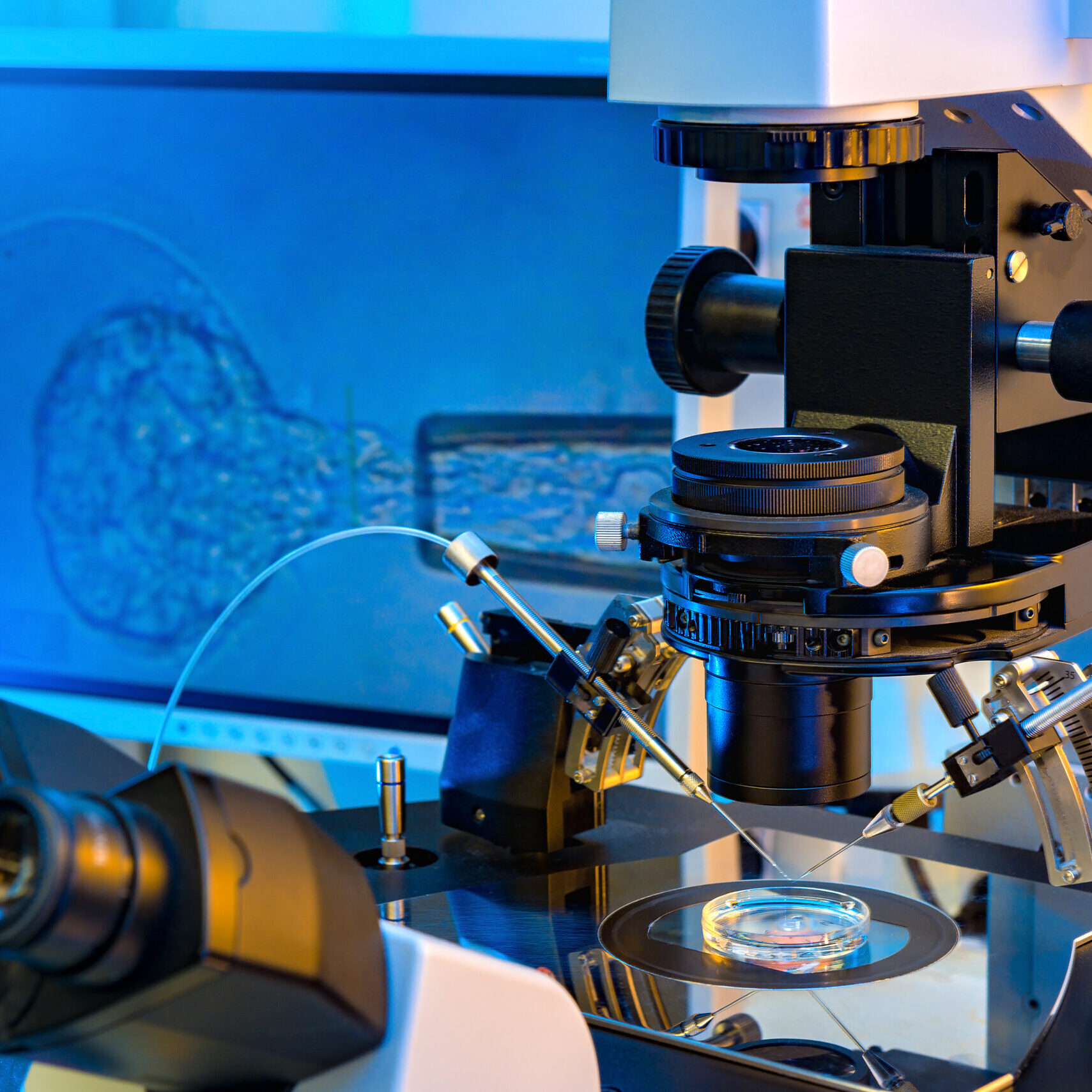 A Professional In Vitro Fertilisation Microscope with A Monitor in Background